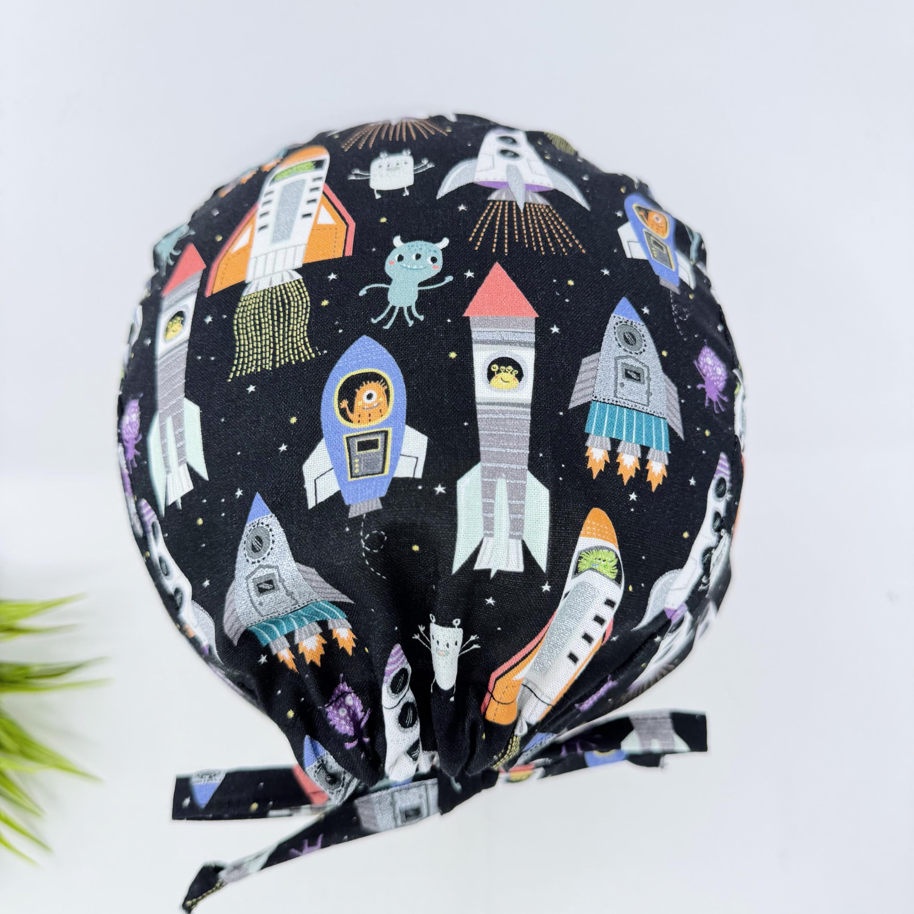 Men's surgical scrub cap. Black Space Rocket Print skull tie-back style scrub hat by Paradise Caps.