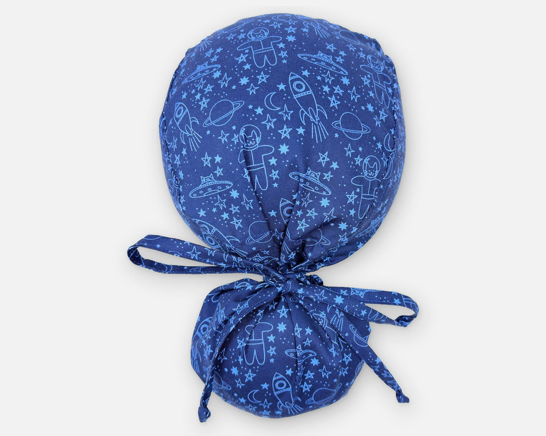 Space Cat Ponytail scrub cap in blue with cats, rockets and stars, viewed from above