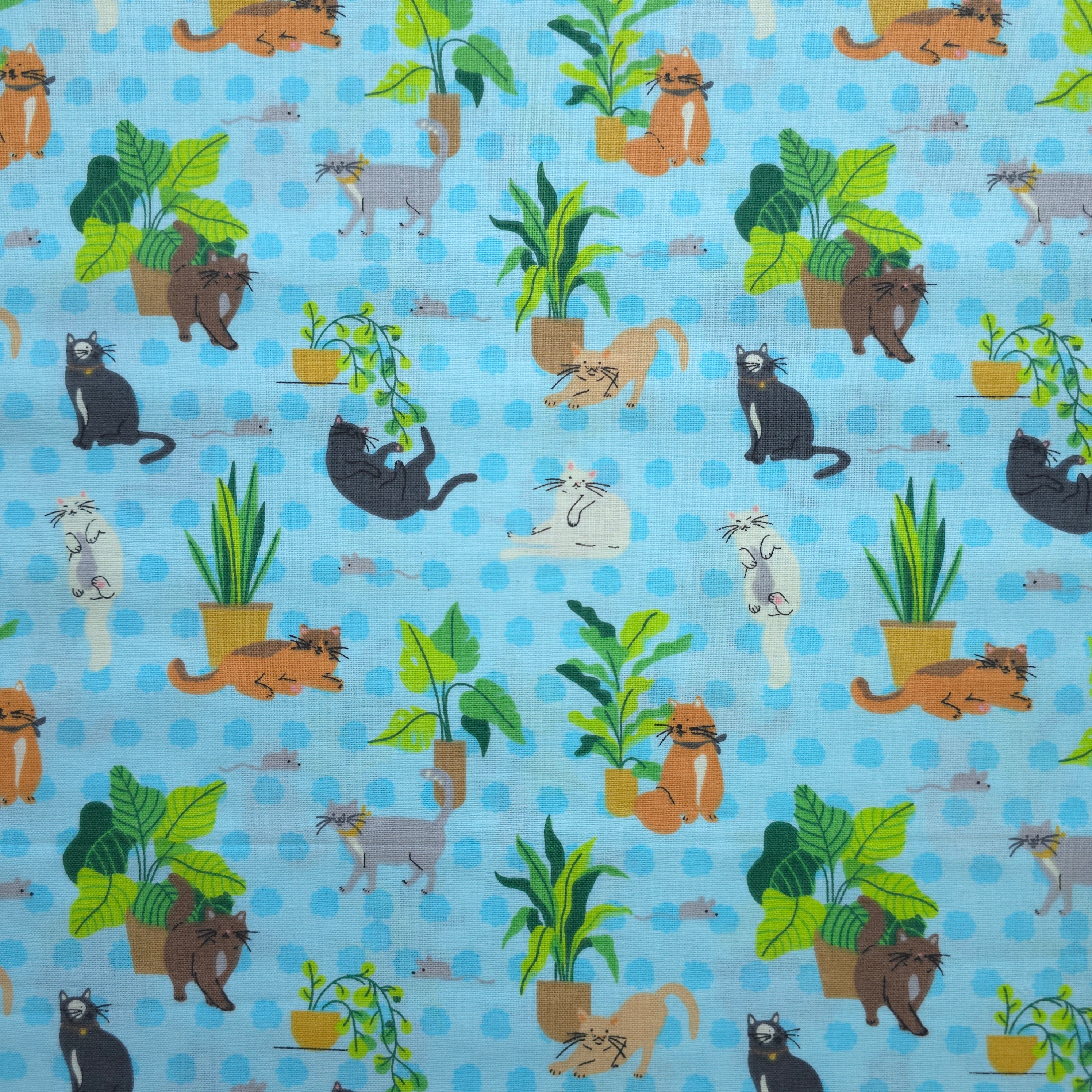 Patterned fabric with cartoon cats and plants on a blue background