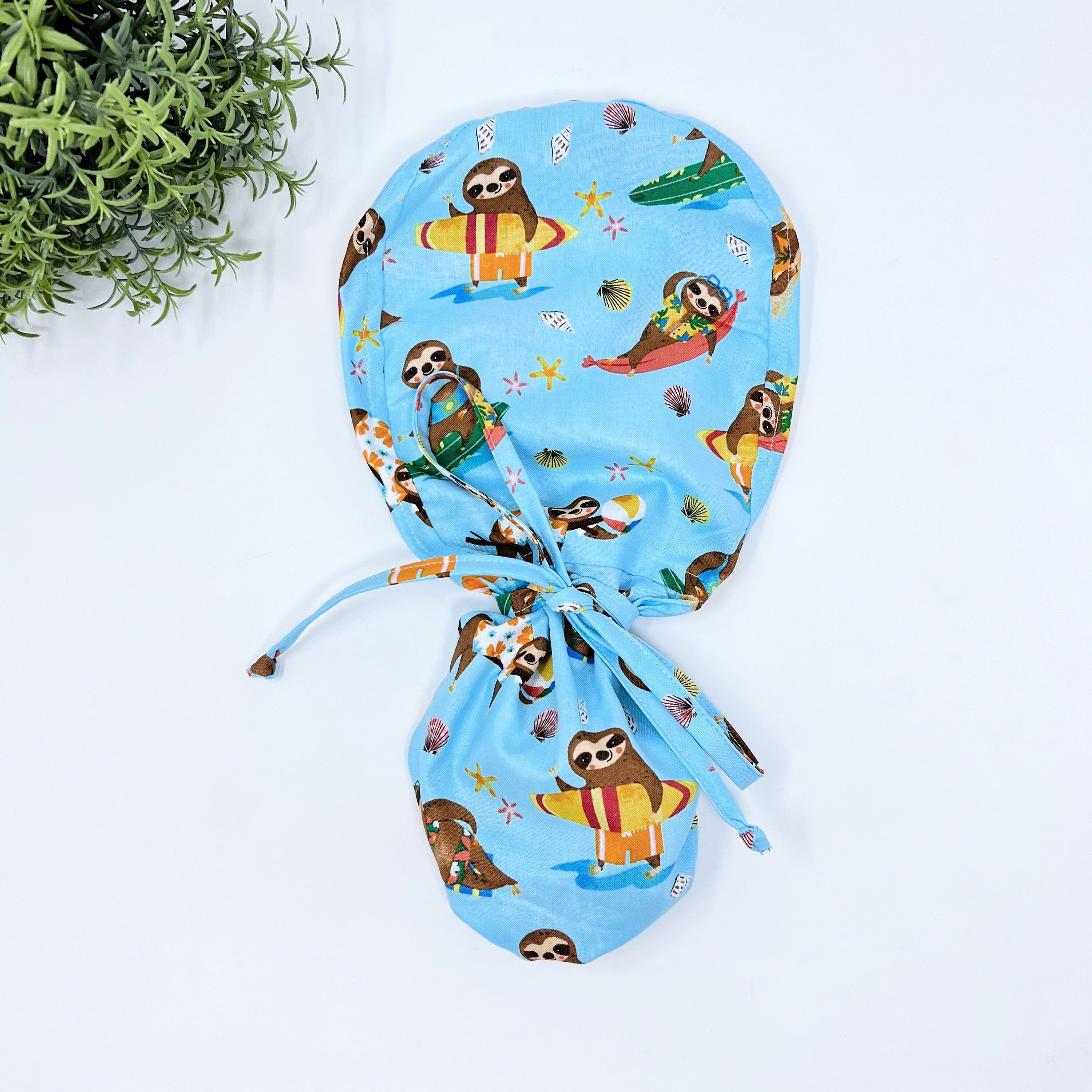 Summer ponytail scrub cap for women. Funny Ponytail scrub hat. Surfing sloths scrub hat with satin lined option by Paradise Caps.