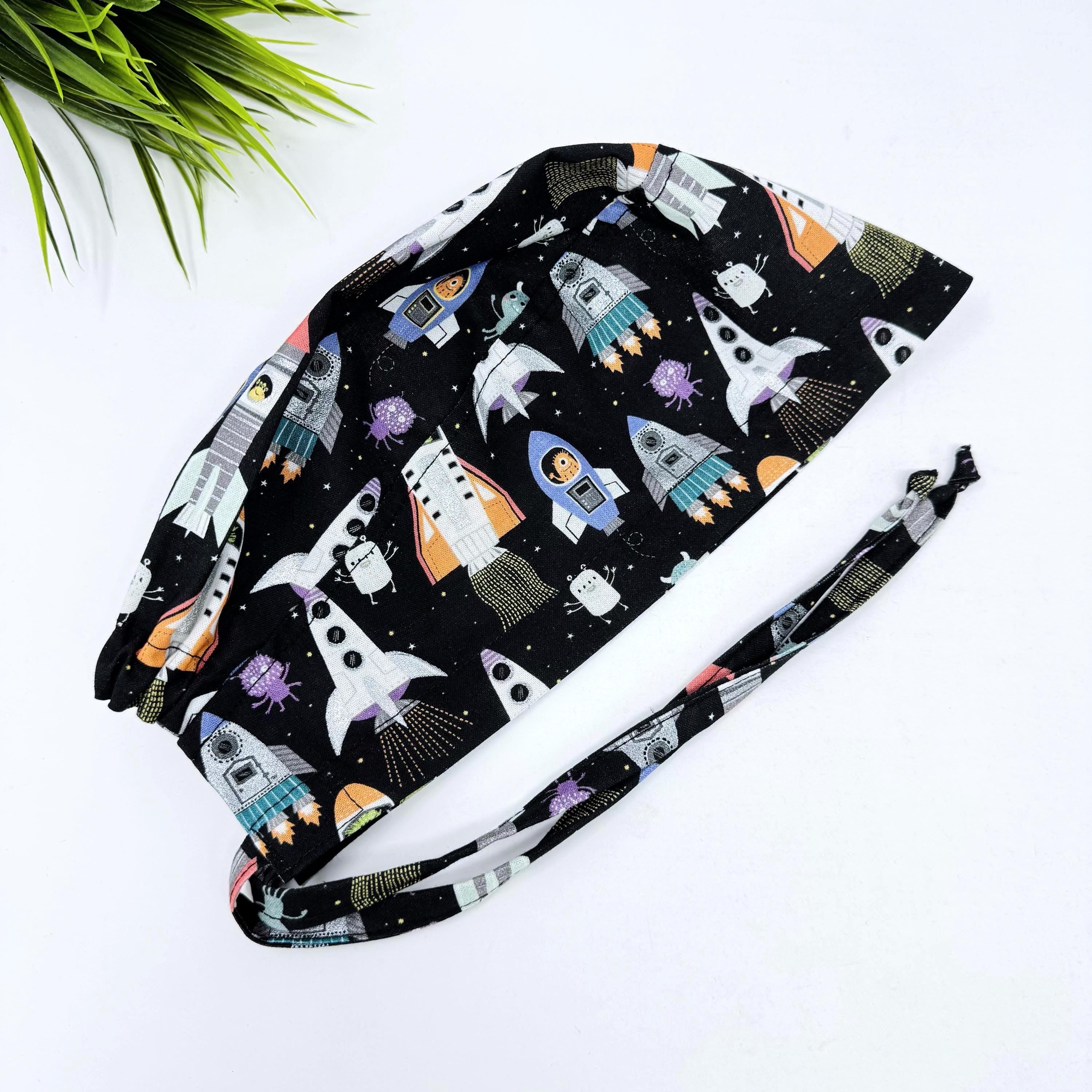 Men's surgical scrub cap. Black Space Rocket Print skull tie-back style scrub hat by Paradise Caps.