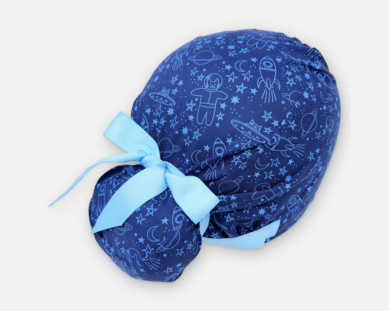 Blue cotton Euro Plus scrub cap with space cats, rockets and stars, shown from the rear three-quarter angle with a light blue ribbon bow.