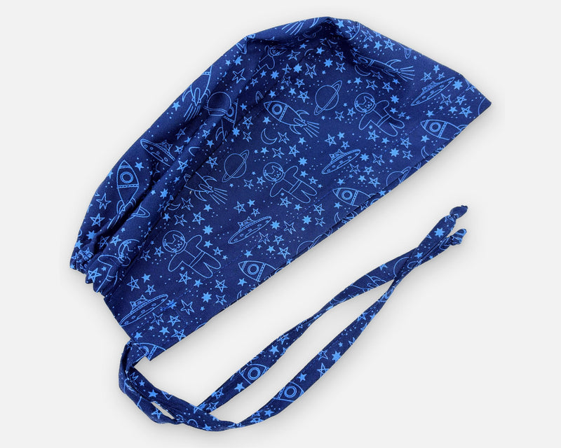 Navy blue cotton surgical scrub cap with space cats, rockets, planets and stars, shown diagonally with matching fabric ties.