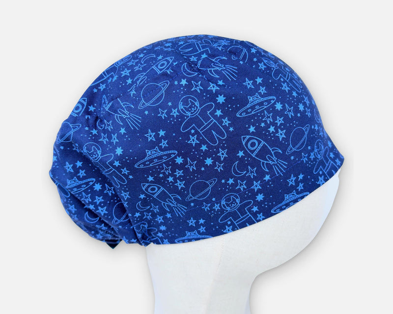 Blue cotton Euro scrub cap with space cats, rockets, planets and stars, shown in profile on a fabric mannequin.